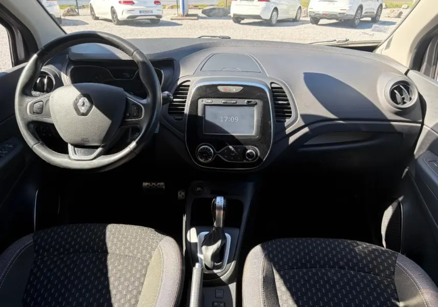 Vue intérieure avant du Renault Captur gris 2017, avec volant multifonctions, écran tactile et boîte automatique visible.