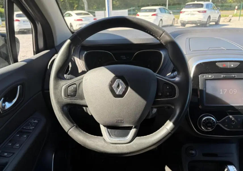 Vue centrée sur le volant multifonctions noir du Renault Captur gris, avec tableau de bord et écran tactile visibles.