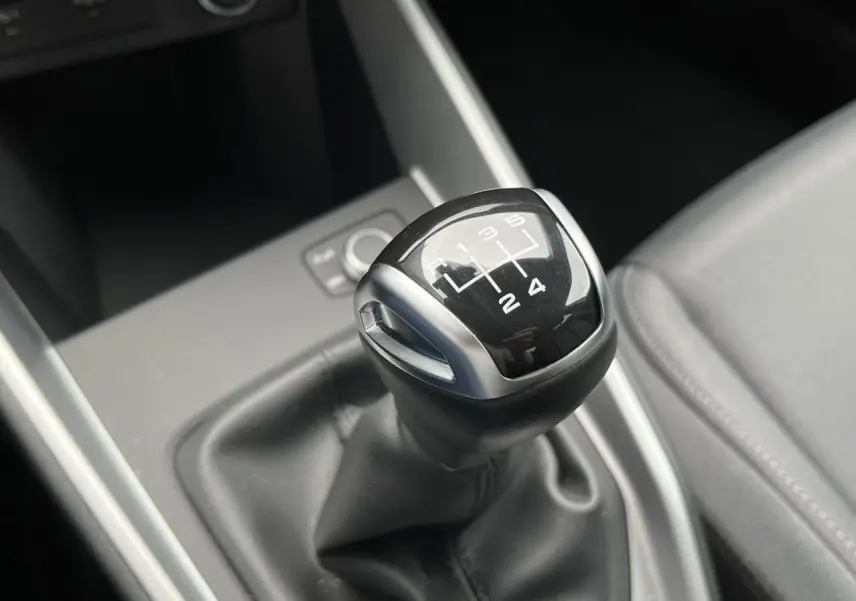 Le levier de vitesses manuel noir de l'Audi A1 Allstreet 25 TFSI, vu en gros plan depuis l'intérieur.