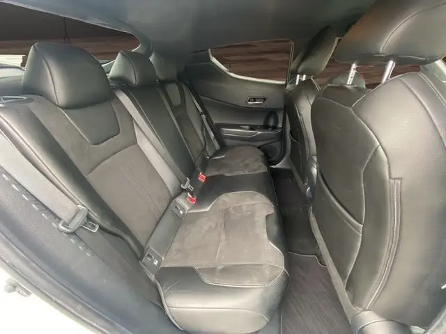 Vue intérieure arrière du Toyota C-HR Hybride 2018, sièges noirs en cuir et tissu, ambiance sobre et moderne.