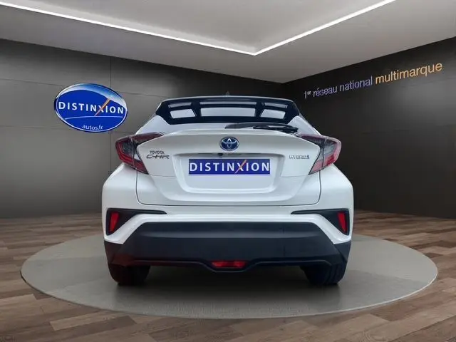 Vue arrière d'un Toyota C-HR Hybride blanc avec toit noir, mettant en valeur ses feux arrière et son design compact.