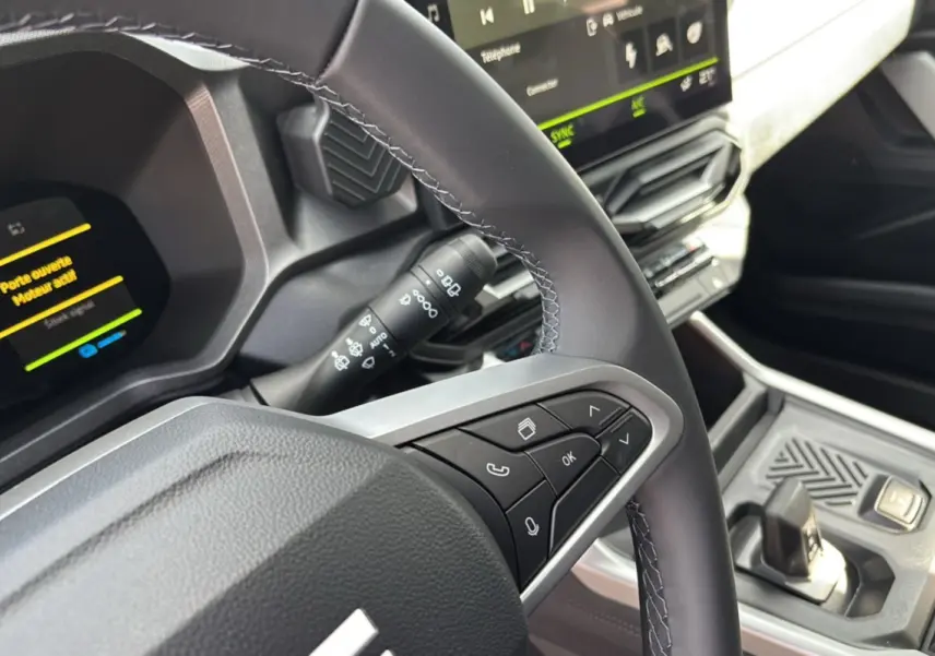 Gros plan sur le volant cuir et commandes multifonctions du tableau de bord digital du Dacia Bigster Hybrid 155 Journey Plus.
