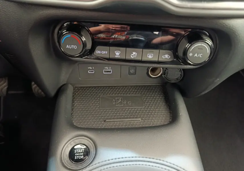 Vue rapprochée de la console centrale noire du Nissan Juke 2025 avec commandes climatisation et bouton start/stop.