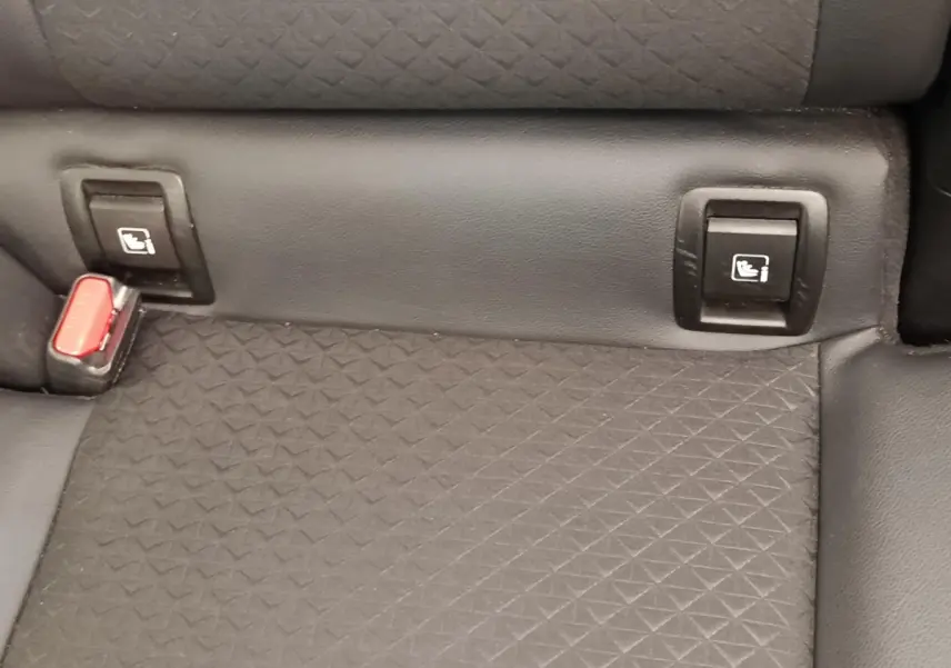 Gros plan sur la banquette arrière noire du Nissan Juke avec fixation Isofix et boucle de ceinture rouge visible.