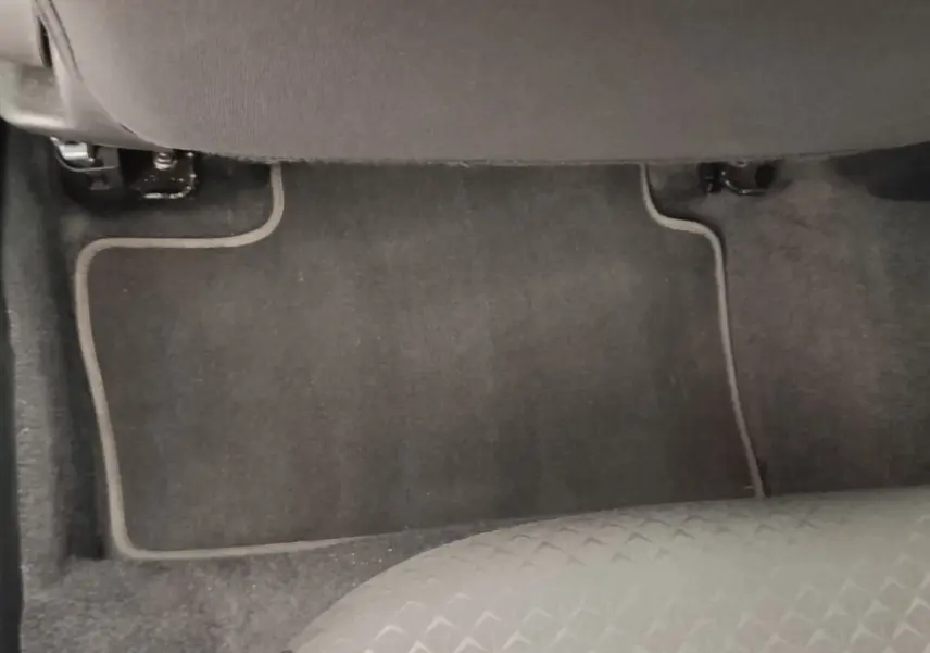 Vue rapprochée du tapis de sol gris foncé et de la partie inférieure du siège avant d’un Nissan Juke gris clair.