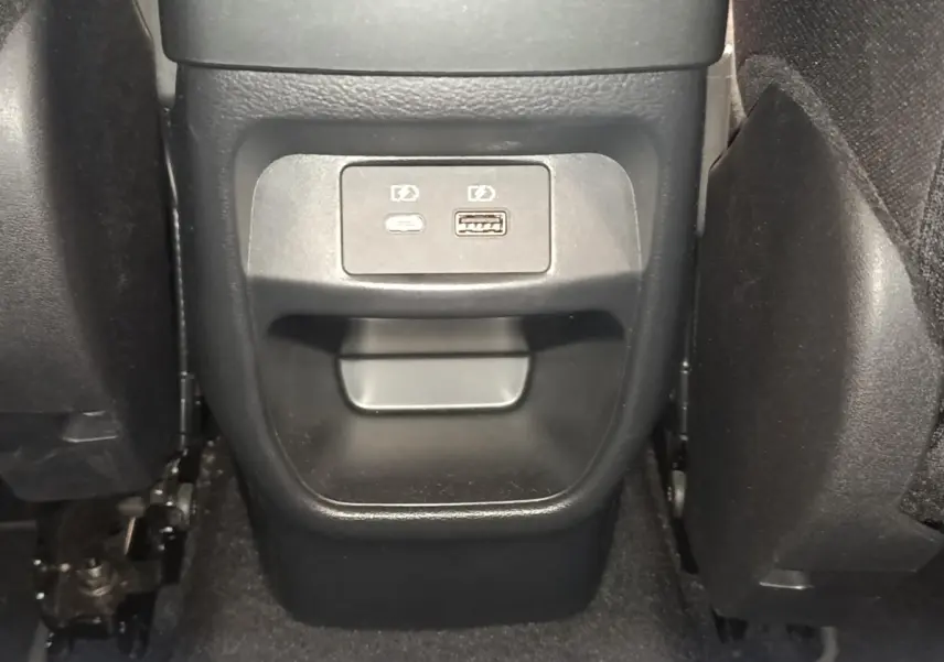Vue rapprochée des ports USB arrière noirs situés entre les sièges arrière du Nissan Juke gris clair 2025.