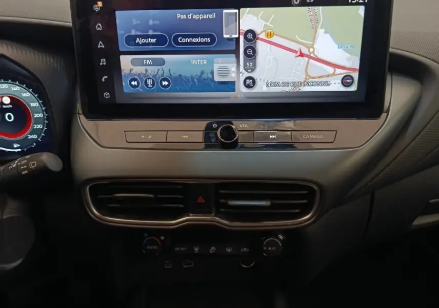 Vue intérieure centrée sur la console centrale du Nissan Juke gris clair 2025 avec écran tactile et boîte manuelle.