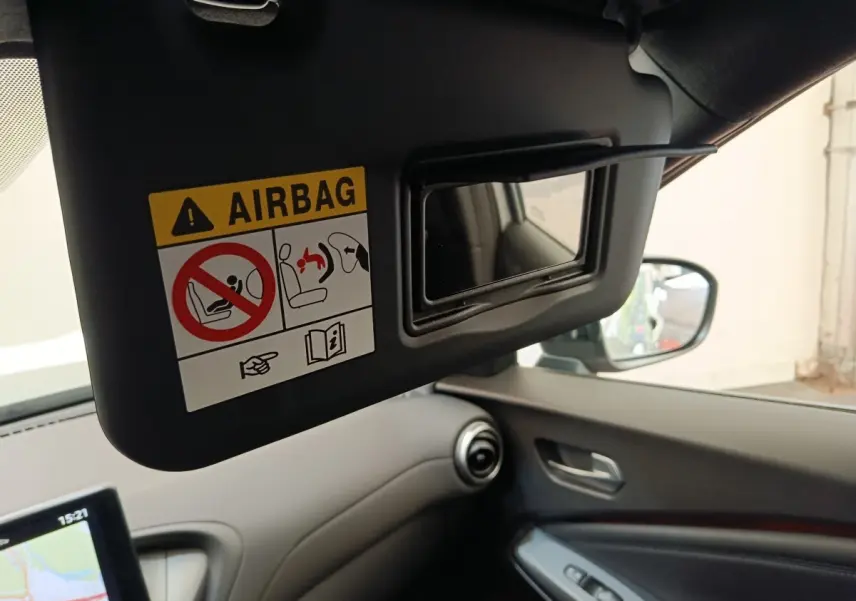 Vue intérieure du pare-soleil côté conducteur avec miroir et avertissement airbag dans un Nissan Juke gris clair.