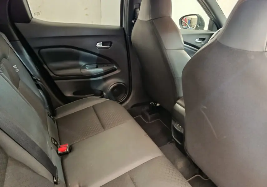 Vue intérieure côté gauche sur la banquette arrière noire du Nissan Juke 2025 avec ceintures et porte arrière visible.
