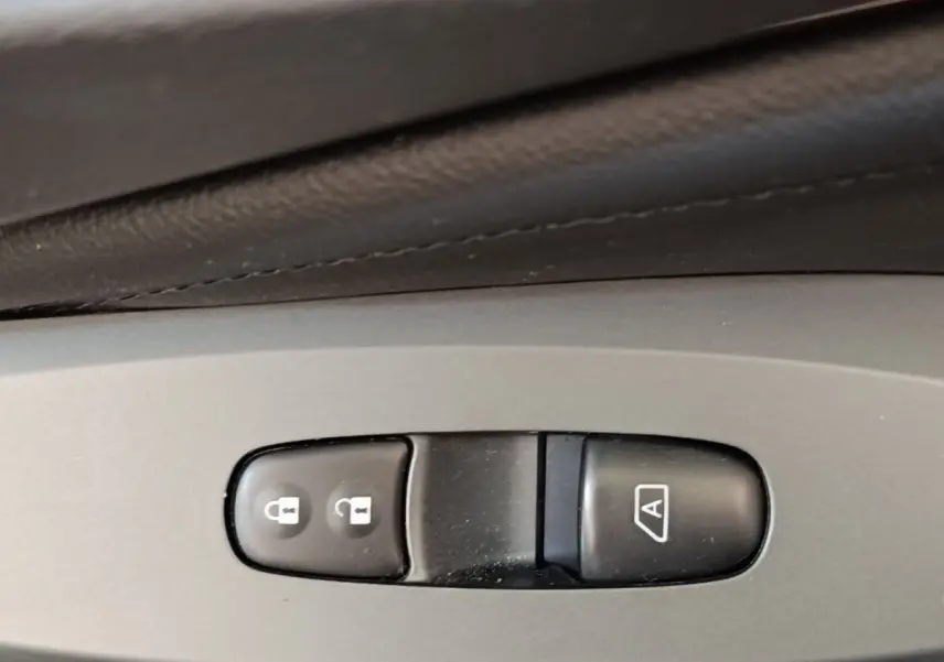 Gros plan sur les boutons de verrouillage central et de démarrage automatique du moteur dans un Nissan Juke gris clair 2025.