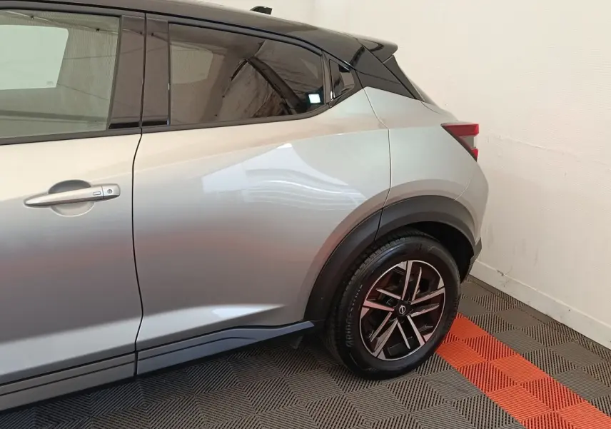 Vue latérale côté gauche sur l'arrière d'un Nissan Juke gris clair avec jante alliage noire et toit noir.