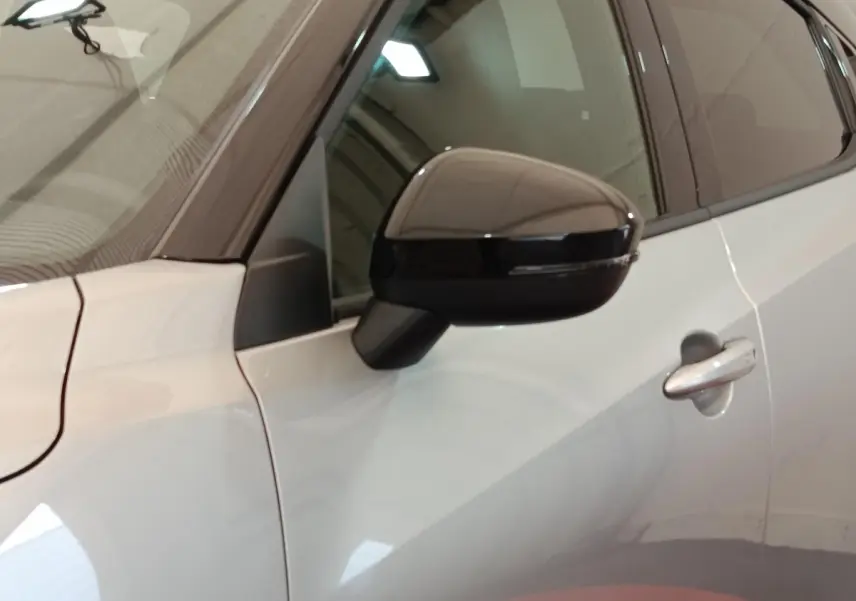 Vue rapprochée du rétroviseur et de la portière côté gauche d’un Nissan Juke gris clair 2025.