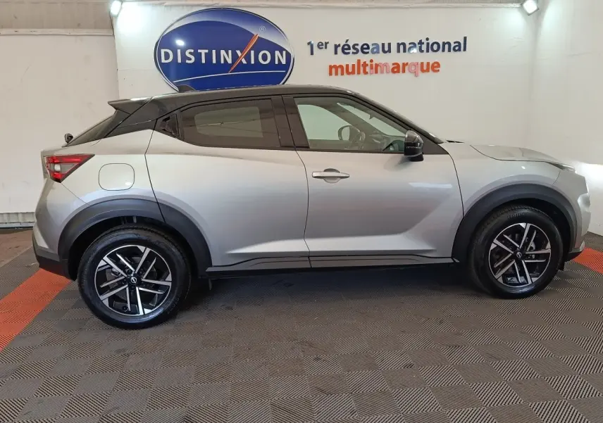 Profil droit d'un Nissan Juke 2025 gris clair avec toit noir, jantes alliage et protections d'ailes noires.