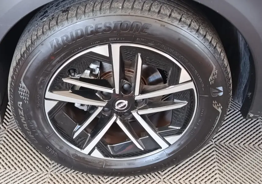 Gros plan sur la jante alliage noire et argentée du Nissan Juke gris clair, avec pneu Bridgestone visible.