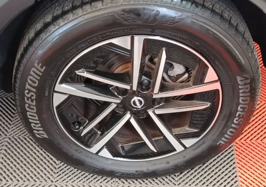 Gros plan sur la jante noire et argentée d’un Nissan Juke gris clair avec pneu Bridgestone visible de face.