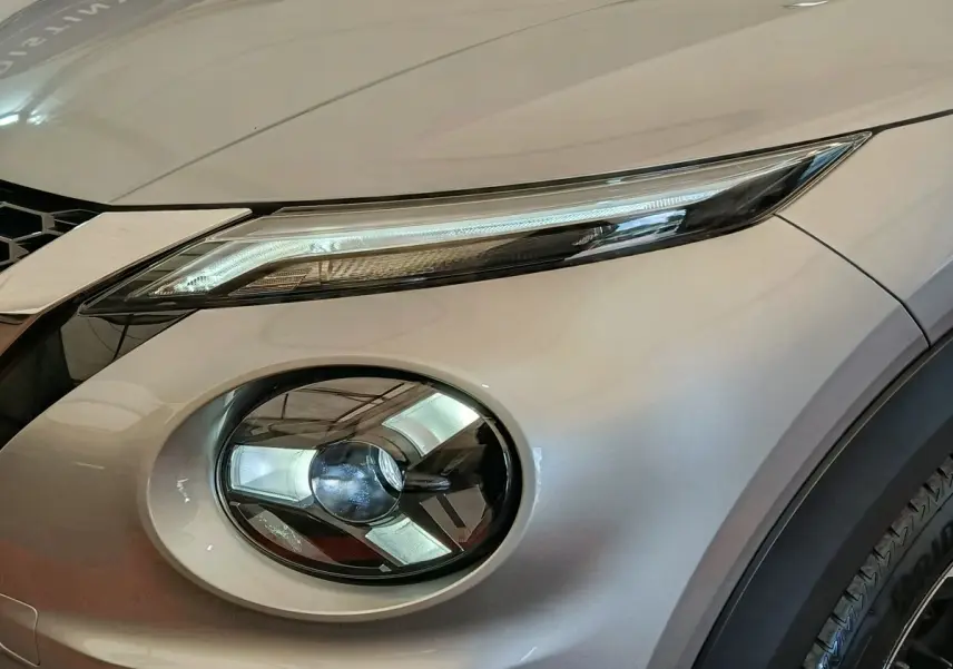 Gros plan sur le phare avant droit du Nissan Juke gris clair 2025, mettant en valeur ses feux LED distinctifs.
