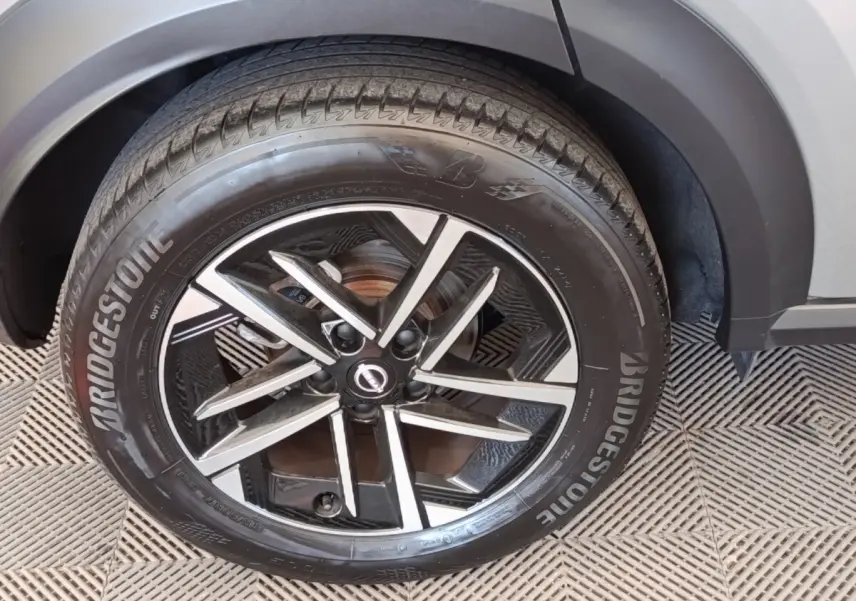 Gros plan sur la roue avant droite du Nissan Juke gris clair 2025 avec jante alliage noire et argentée Bridgestone.