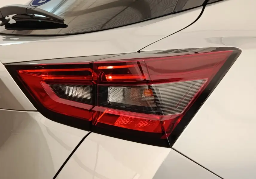 Gros plan sur le feu arrière droit rouge et blanc d’un Nissan Juke gris clair 2025, vue de profil arrière.