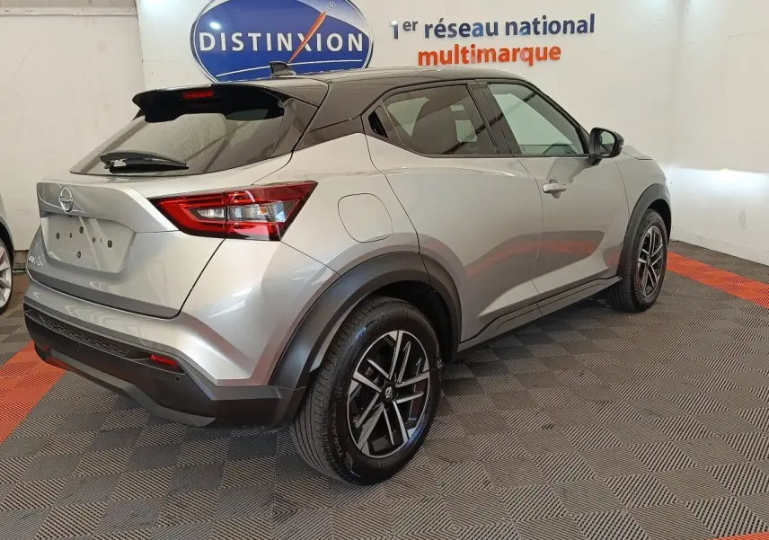 Nissan Juke gris clair vu en 3/4 arrière droit, avec jantes alliage noires et toit noir contrasté.