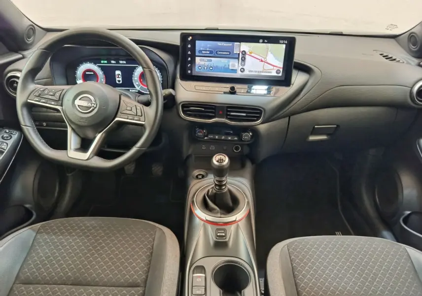 Vue intérieure avant du Nissan Juke 2025 gris clair, avec tableau de bord numérique et écran tactile central large.