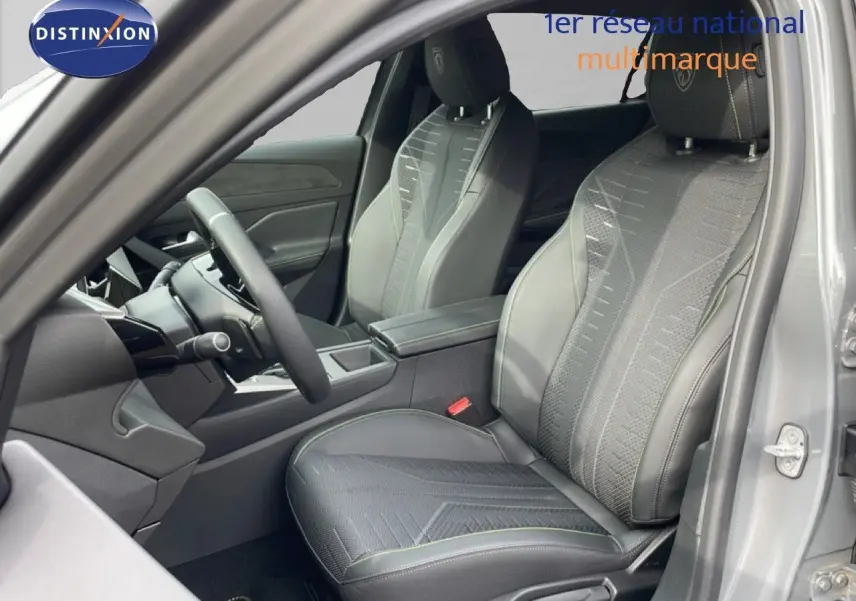 Vue intérieure côté conducteur de la Peugeot 308 gris selenium, sièges tissu cuir avec surpiqûres vertes et volant multifonction.