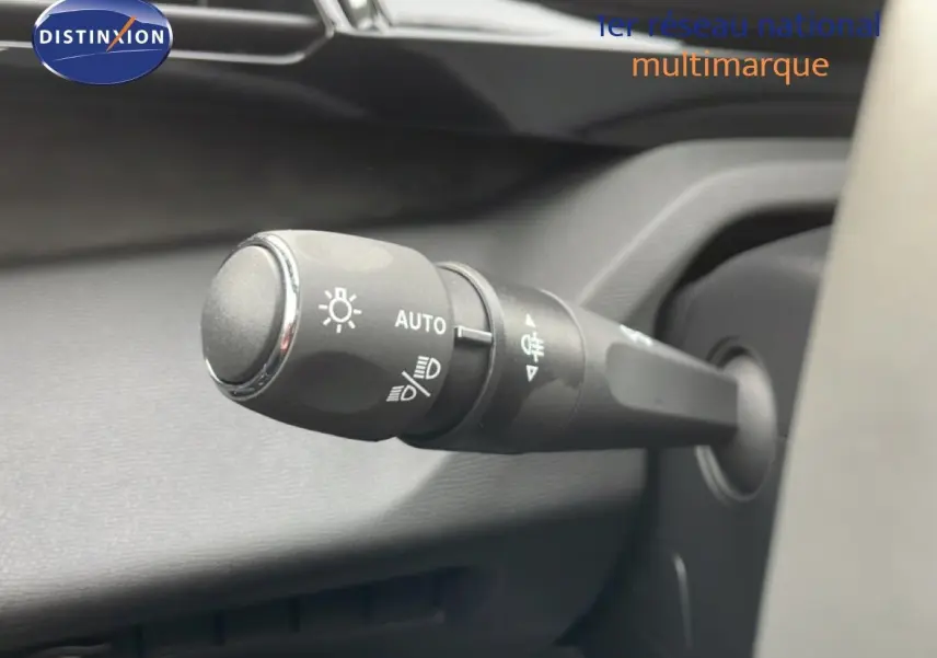 Gros plan sur la commande des phares du Peugeot 308 gris selenium métal, intérieur noir, vue côté gauche du volant.