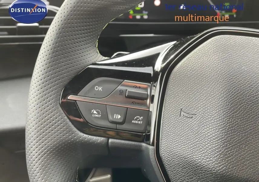 Gros plan sur le volant perforé côté gauche du Peugeot 308 gris Selenium, avec commandes de régulateur et assistant.
