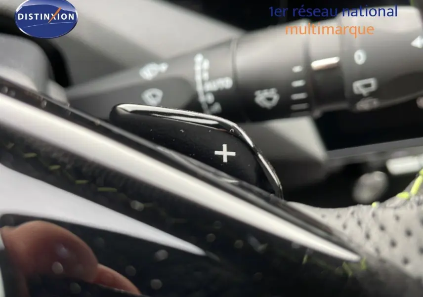 Gros plan sur la palette de changement de vitesse "+" du volant d'une Peugeot 308 gris selenium, intérieur noir.
