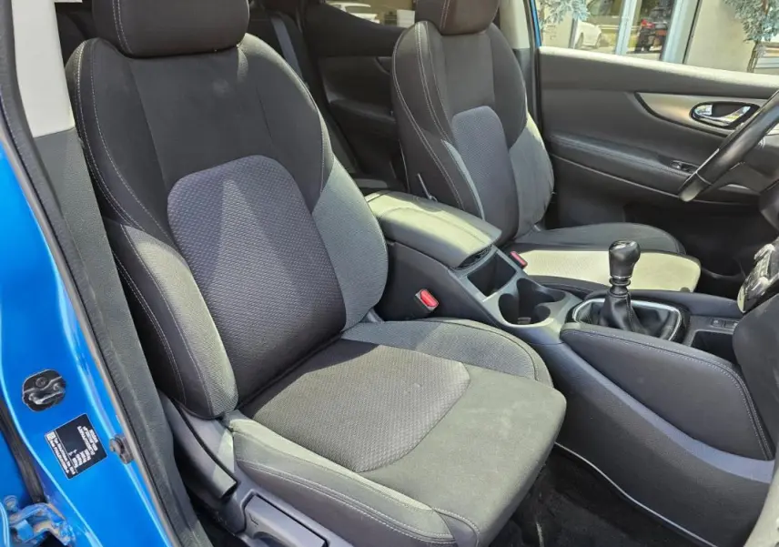 Vue intérieure côté conducteur du Nissan Qashqai bleu 2019, montrant les sièges noirs et la boîte manuelle.
