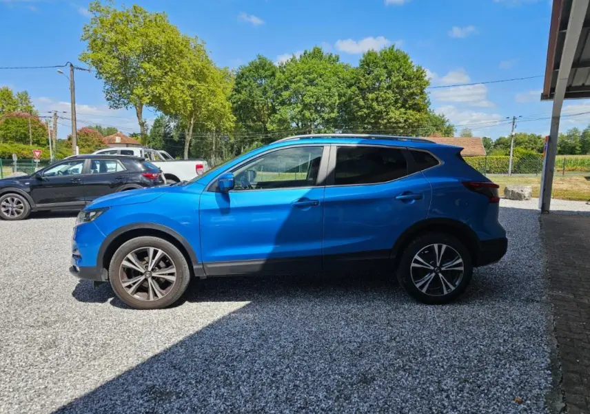 Vue de profil côté gauche d'un Nissan Qashqai bleu 2019 avec jantes alliage et toit noir partiel.