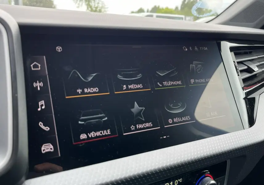 Écran tactile central de l'Audi A1 Sportback 25 TFSI rouge Misano, affichant le menu multimédia et réglages.