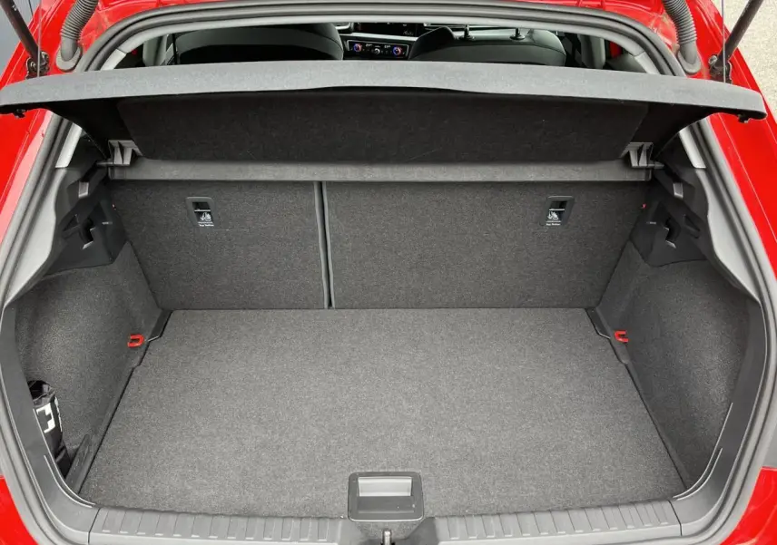 Coffre ouvert vu de l'arrière d'une Audi A1 Sportback rouge Misano, intérieur gris et banquette rabattable.