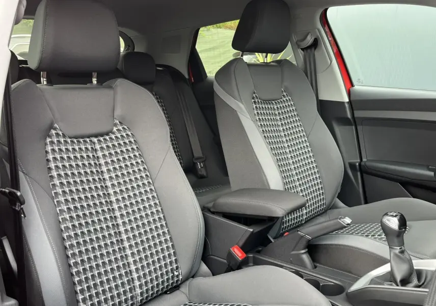 Vue intérieure des sièges avant gris à motifs géométriques de l'Audi A1 Sportback rouge Misano, avec accoudoir central.