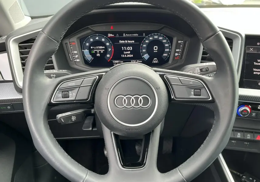 Vue intérieure centrée sur le volant cuir multifonctions et la console centrale de l'Audi A1 Sportback 25 TFSI rouge Misano 2022.