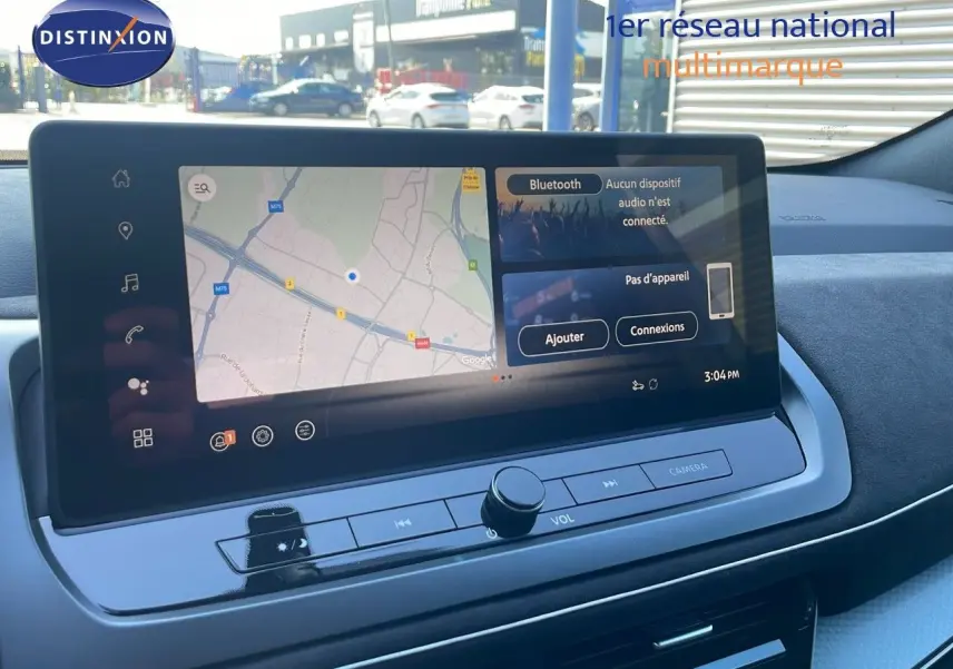 Vue rapprochée de l'écran tactile central du Nissan Qashqai 2025 gris céramique avec toit noir, affichant la navigation et Bluetooth.