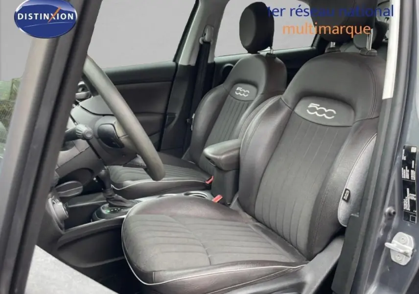 Vue intérieure côté conducteur du Fiat 500X gris foncé, sièges en cuir noir avec logo 500 brodé.