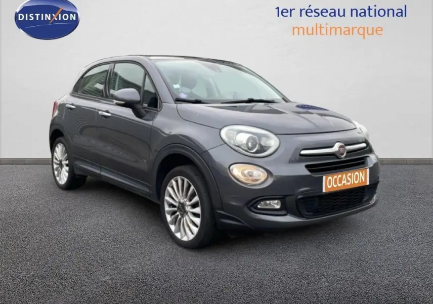 Fiat 500X gris foncé vue 3/4 avant droit, avec jantes alliage 18 pouces et plaque occasion visible.