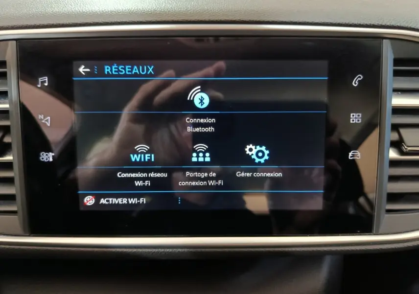 Écran tactile central de la Peugeot 308 blanc affichant les options de connexion Bluetooth et Wi-Fi, vue de face.