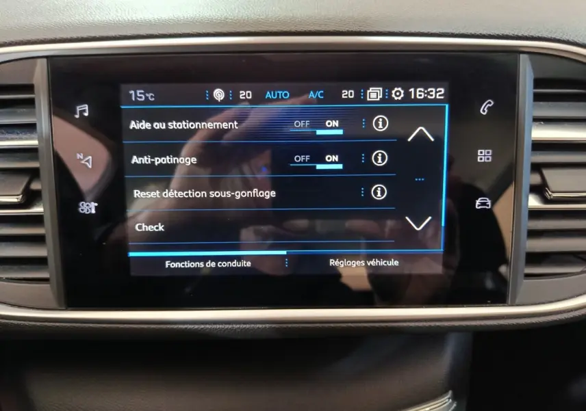Écran tactile central de la Peugeot 308 blanc, affichant les réglages d'aide au stationnement et antipatinage.