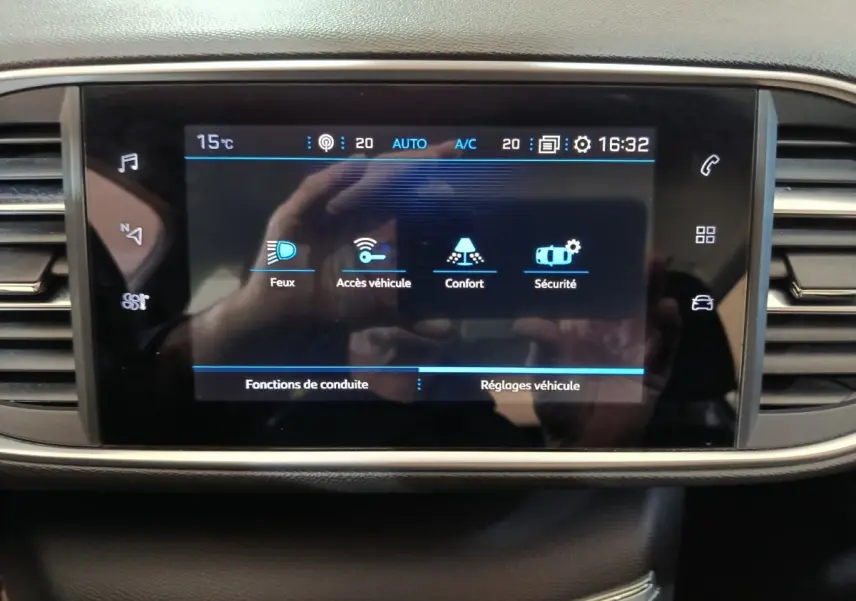 Écran tactile central affichant les réglages de conduite et véhicule dans l'habitacle d'une Peugeot 308 blanche.