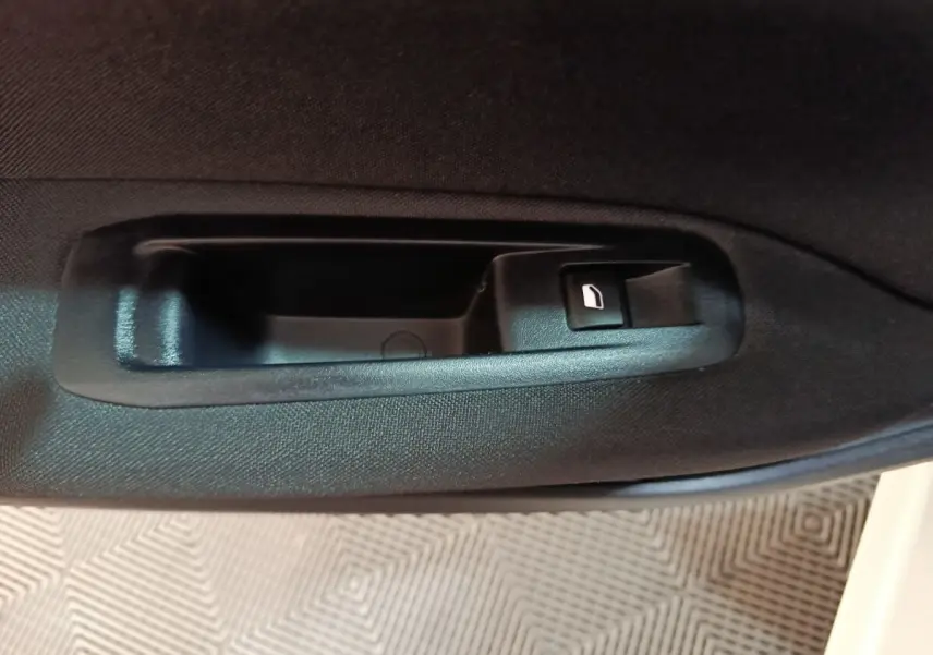 Gros plan sur la poignée intérieure noire de la porte côté gauche d'une Peugeot 308 blanche de 2021.