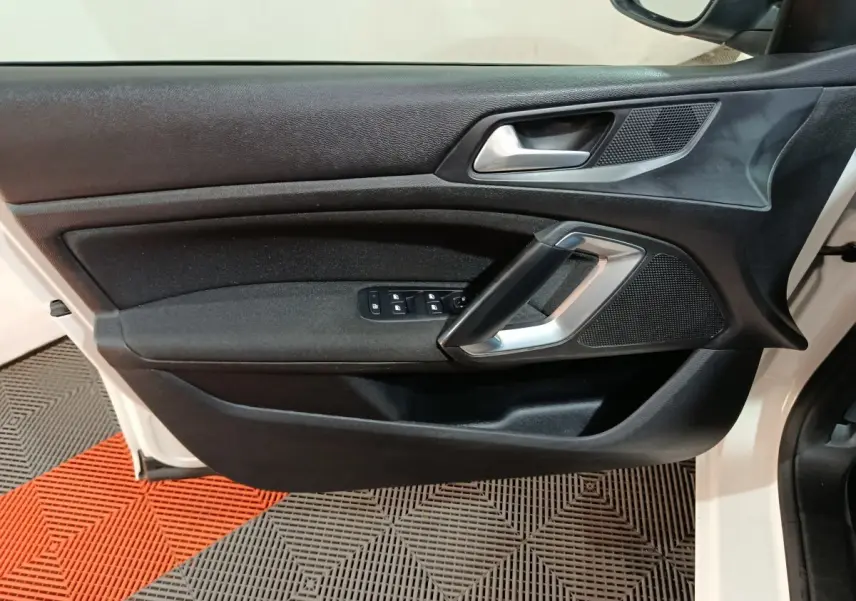 Vue rapprochée de la porte avant gauche blanche du Peugeot 308 2021, avec commandes électriques et poignée argentée.