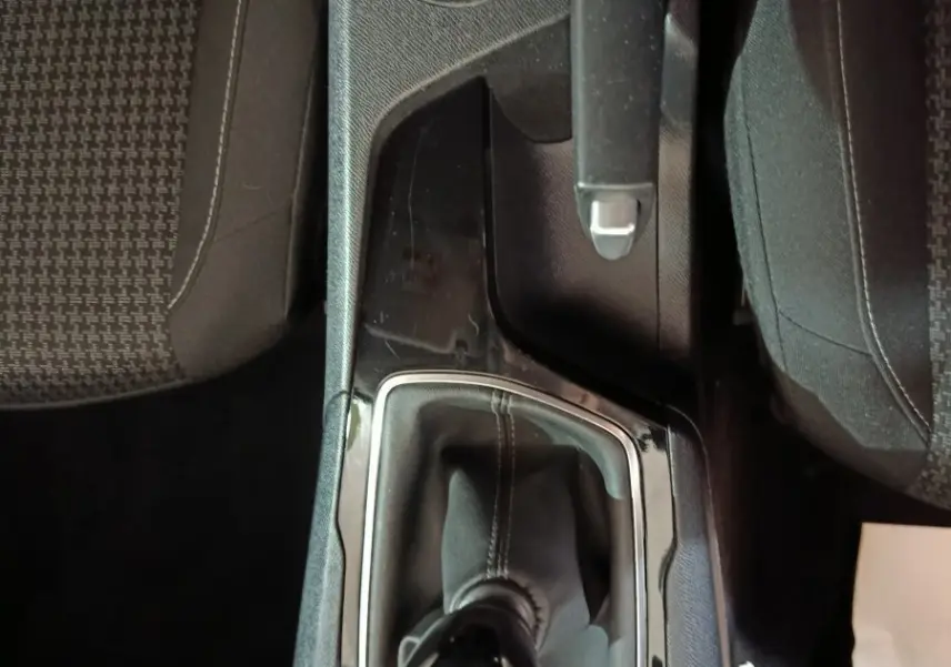 Vue plongeante sur la console centrale noire de la Peugeot 308 blanche, mettant en valeur le levier de vitesse manuel.