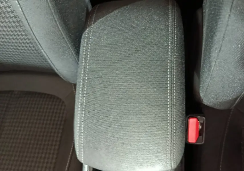 Vue plongeante sur l'accoudoir central noir et porte-gobelet entre les sièges avant de la Peugeot 308 blanche.