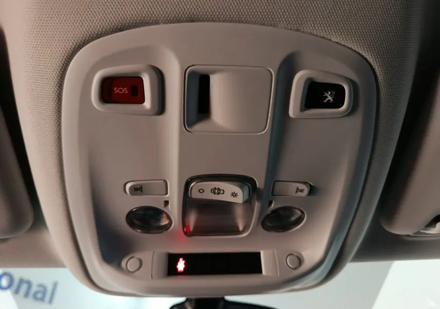 Vue en gros plan du plafonnier intérieur blanc avec bouton SOS et logo Peugeot éclairé sur une Peugeot 308 blanche.