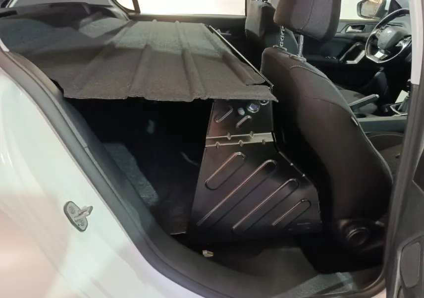 Vue intérieure côté gauche du coffre avec cloison rigide et sièges avant noirs dans une Peugeot 308 blanche 2021