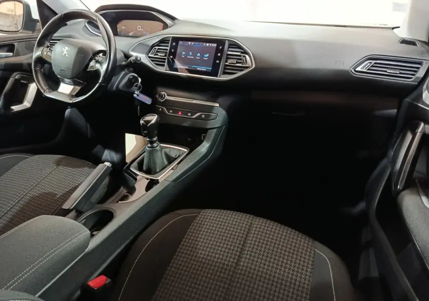 Intérieur noir de la Peugeot 308 BlueHDi 130, vue côté conducteur montrant volant cuir et écran tactile central.