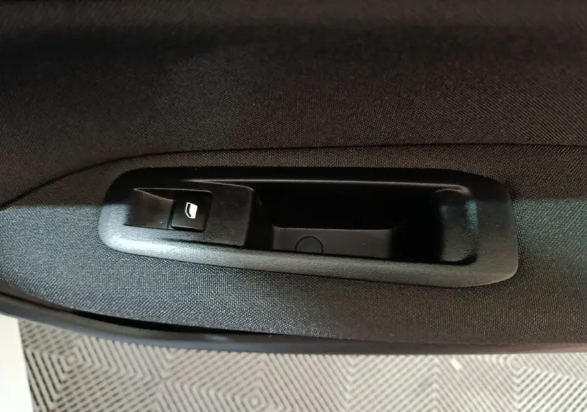 Gros plan sur le bouton de commande de lève-vitre côté conducteur dans l'habitacle noir de la Peugeot 308 blanche.