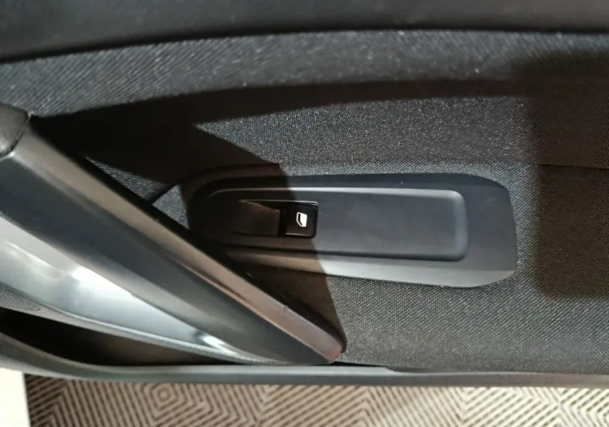 Gros plan sur la commande de lève-vitre côté gauche d'une Peugeot 308 blanche, intérieur tissu noir.