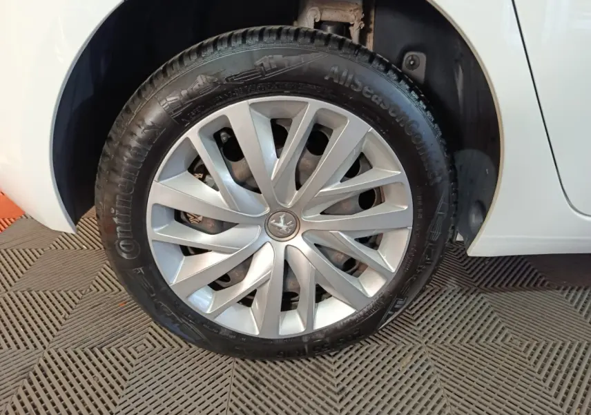 Gros plan sur la roue avant gauche d’une Peugeot 308 blanche, mettant en valeur la jante en alliage et le pneu Continental.